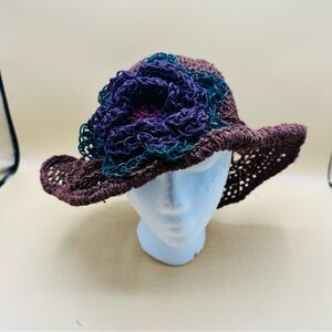 Handmade, crocheted sun hat with a purple and teal flower accent